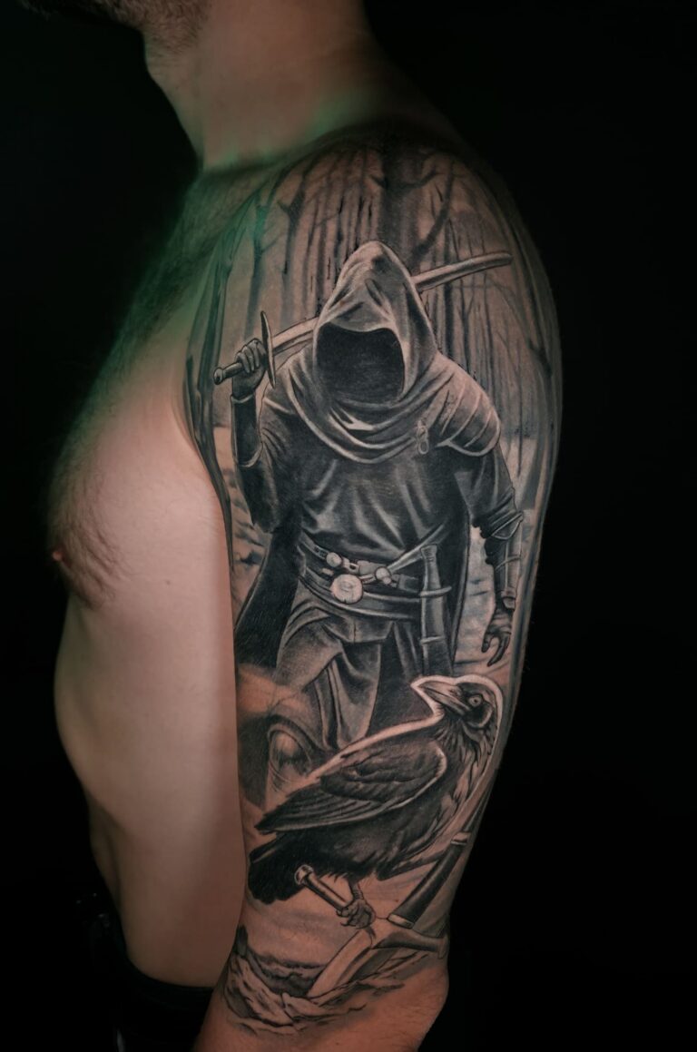 Black and grey realistic tattoo sleeve featuring a hooded warrior, raven, and dark forest scene covering an old wolf tattoo on the upper arm